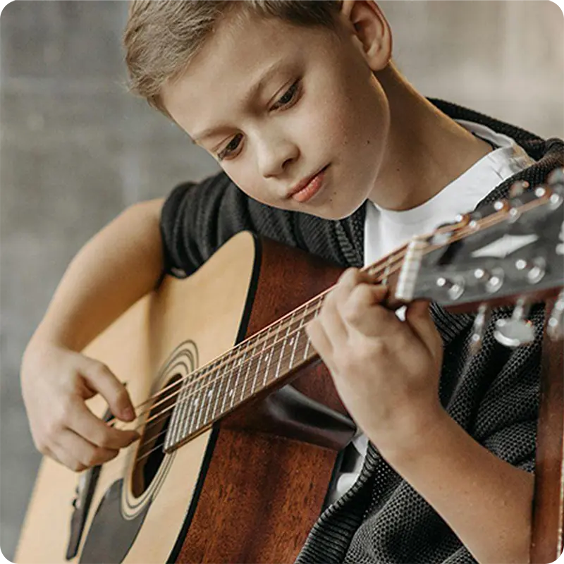 A young boy playing an acoustic guitar
