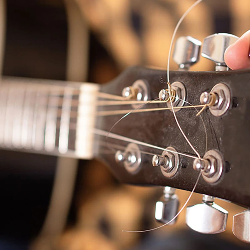   A child tuning a guitar using a clip-on tuner.  