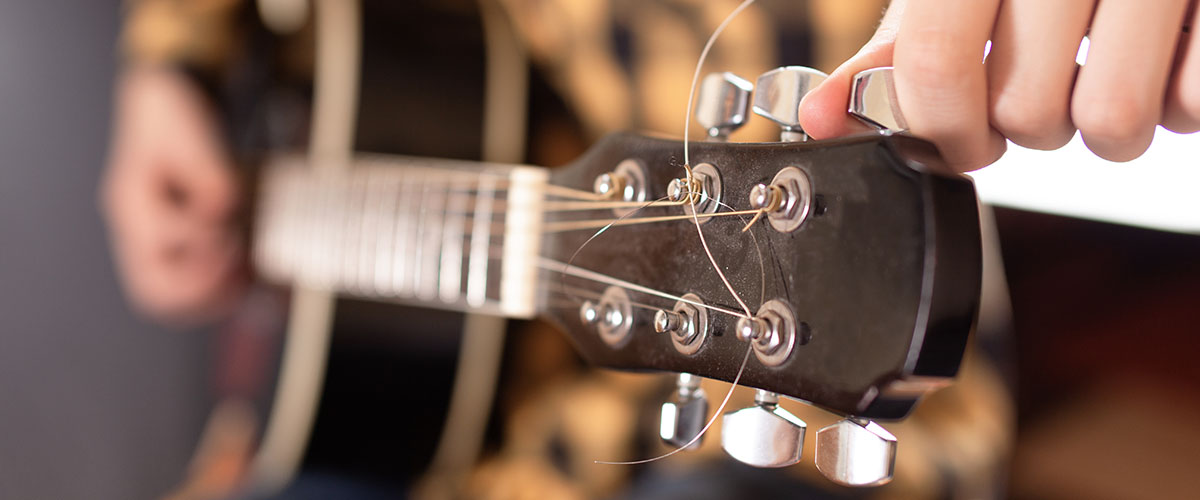  A child tuning a guitar using a clip-on tuner. 